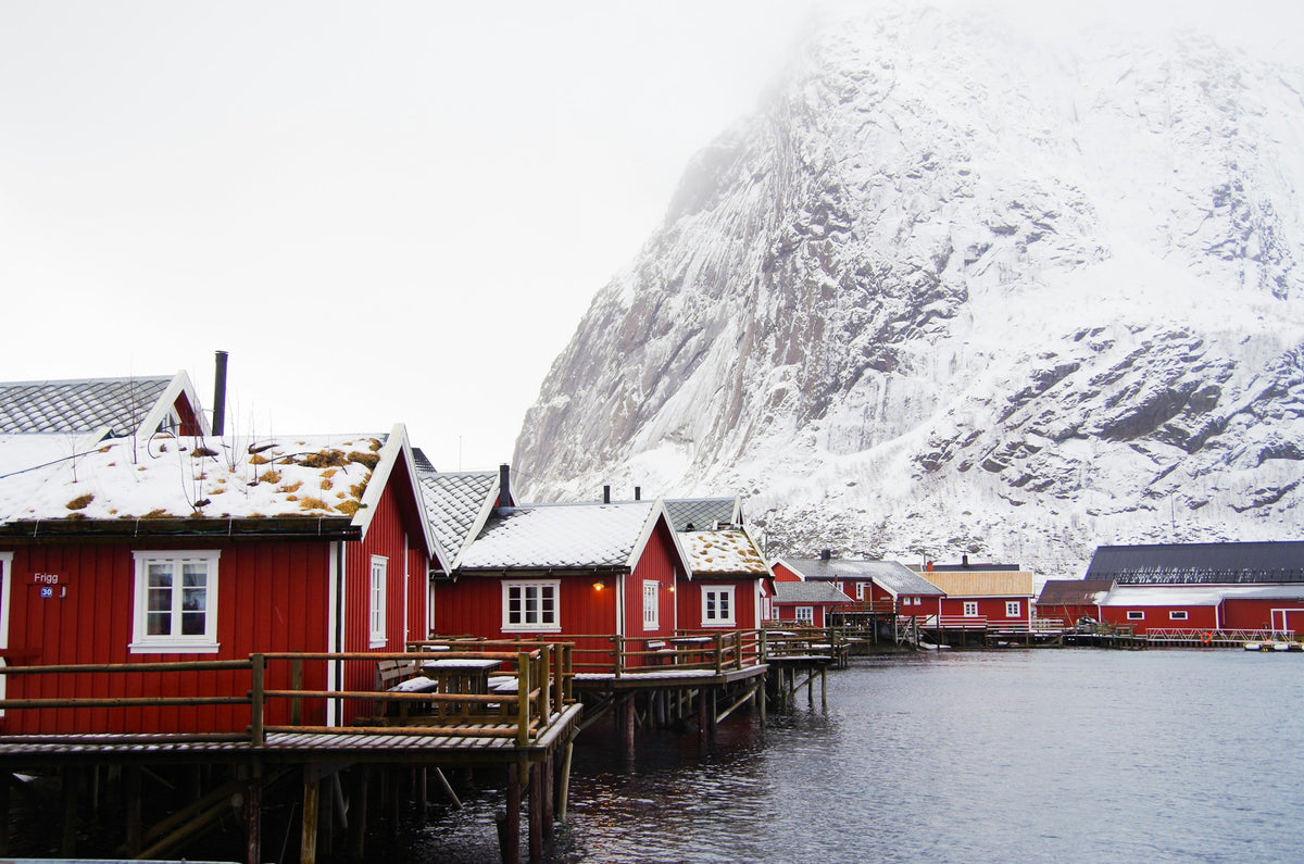 Rote Fischerhütten vor verschneiten Bergen auf den Lofoten